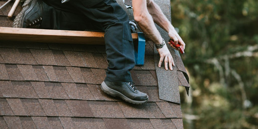 a man on a roof working and wearing roofing shoes